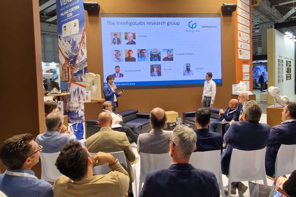 Due persone che presentano una slide, davanti ad una platea di persone sedute